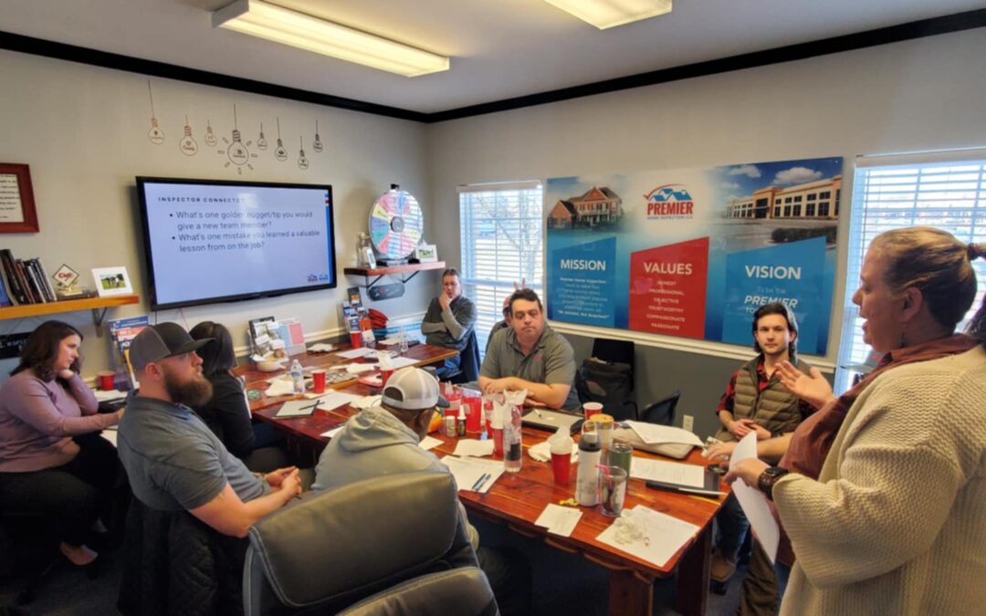 Ginger, co owner of Premier Home Inspection, leading a team discussion at the annual kickoff meeting. She stands at the front of the room, engaging with the team as they collaborate on goals and strategies for the year ahead.