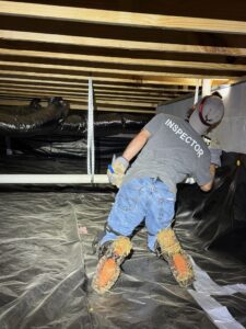 Property inspector in the crawlspace of a home checking for leaks, damage, fungal growth, and other concerns.